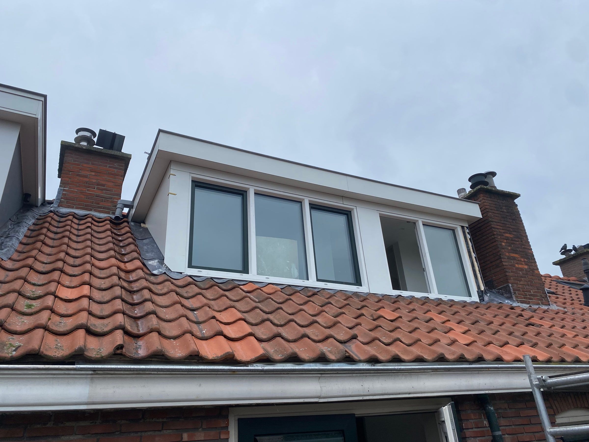 Afgeronde dakkapel op een pannendak, gezien vanaf de straat