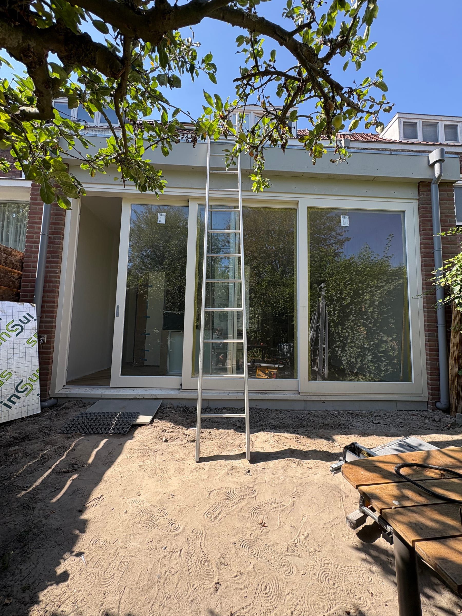 Aanbouw aan de achterkant met een brede schuifpui, gezien vanuit de tuin