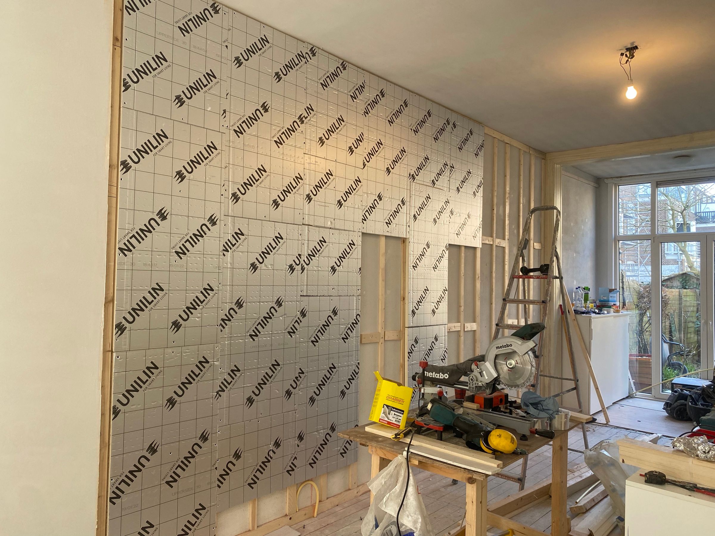 Isolatieplaten tegen een binnenwand, met een verstekzaag op de voorgrond