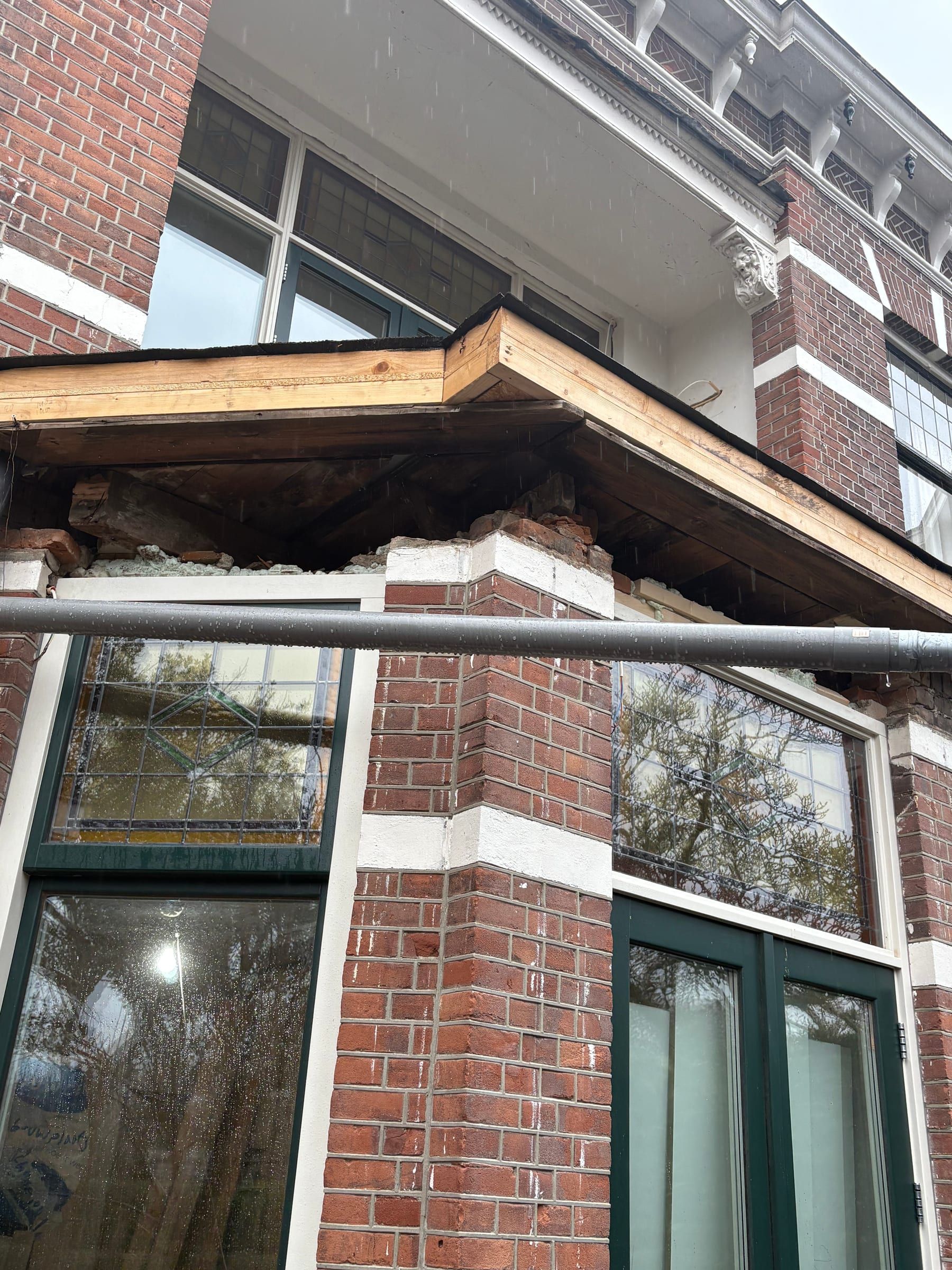 Opengelegde dakrand van een erker: oud metselwerk bloot, nieuw houten frame erop