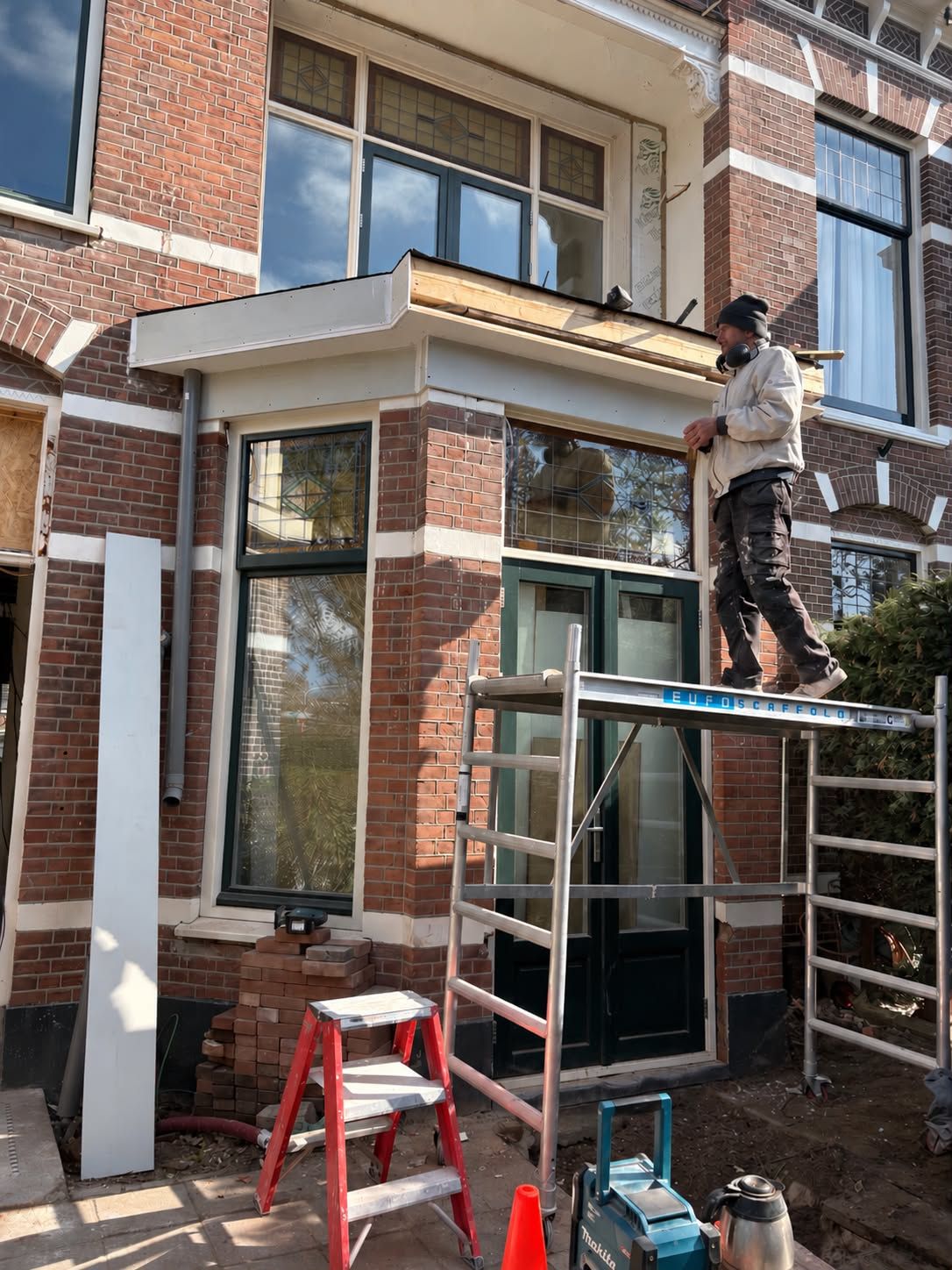 Werk aan de dakrand van de erker, vanaf een rolsteiger
